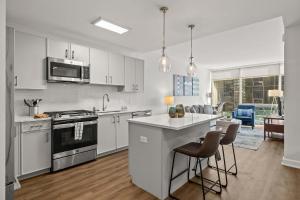 a kitchen with white cabinets and a kitchen island with chairs at Luxury Modern Apartment Near Stamford Station in Stamford