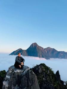 a man sitting on top of a rock on the ocean at Overnight Camping Peak Of Nong Khiaw in Nongkhiaw