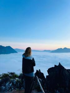 a woman standing on top of a mountain overlooking the ocean at Overnight Camping Peak Of Nong Khiaw in Nongkhiaw