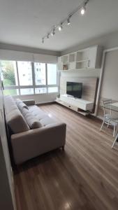 a living room with a couch and a flat screen tv at Apartamento completo e com ar-condicionado in Bento Gonçalves