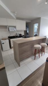 a kitchen with a counter and two stools at Apartamento completo e com ar-condicionado in Bento Gonçalves