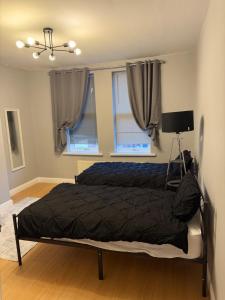 a bedroom with a bed with a black comforter and two windows at Stylish 3 BR home & Game room & Family Lounge in Dudley