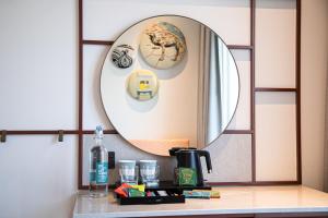 un miroir sur un mur au-dessus d'un comptoir avec une cafetière dans l'établissement Rove Healthcare City - Bur Dubai, à Dubaï