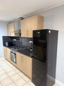 a kitchen with a black refrigerator and wooden cabinets at Stylish 3 BR home & Game room & Family Lounge in Dudley