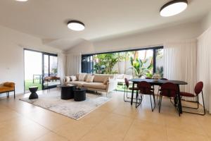 a living room with a couch and a table and chairs at O&O Group - Huge Villa With Jacuzzi By The Beach in Rishon LeẔiyyon +52 photos