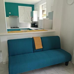 a blue couch in a room with a kitchen at Appartement charmant au Gosier avec jardin de 68 m² in Mare Gaillard