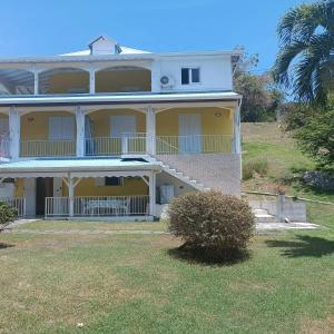 a large yellow house with a balcony and a yard at Appartement charmant au Gosier avec jardin de 68 m² in Mare Gaillard +4 photos