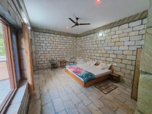 本贾尔Tirthan Valley Cockaigne的一间卧室，床嵌在砖墙里