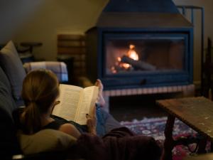 a woman reading a book in front of a fireplace at Finca Fuente Laurel in Arucas