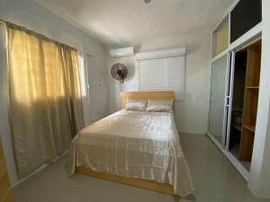 a bedroom with a bed with white sheets and a window at Casa veraniega en samana in Santa Bárbara de Samaná