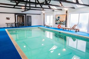 a swimming pool with blue water in a building at The Retreat in Tibenham