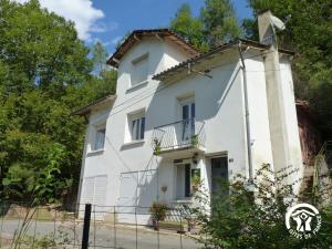 a white house with a balcony and trees at Gîte de la Croix de l'Aveyron in Laguépie