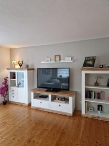 a living room with a television and white shelves at Haus Fuchsbau, Familienzeit und Fokus im Grünen in Kurtscheid
