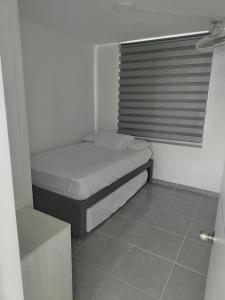ein kleines Schlafzimmer mit einem Bett und einem Fenster in der Unterkunft Aqualina Orange Girardot, décimo piso in Girardot