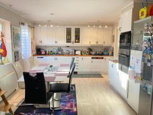 eine Küche mit weißen Schränken und einem Tisch mit Stühlen in der Unterkunft Glamping in a Bungalow Deluxe by the Forest w Swimmingpool near Golf and the Baltic Sea Beach in Järna