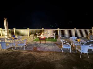 a group of tables and chairs with a fire at night at Hotel Mini Switzerland In Dalhousie in Dalhousie