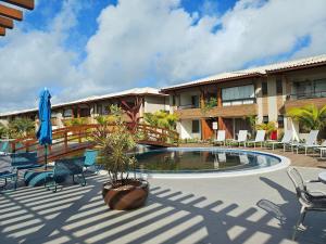 un patio con piscina y sillas y un edificio en Condominio con Piscina a 450m de la Playa en Itacimirim - VBRs, en Pojuquinhos