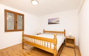 a bedroom with a wooden bed and a window at Stunning Apartment In Mali Losinj With Wifi in Cunski