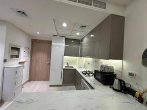 une grande cuisine avec des comptoirs blancs et un évier dans l'établissement Stunning 1 Bed in Meydan, à Dubaï