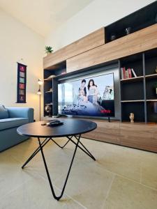 sala de estar con mesa y TV de pantalla grande en Harbour Lights, en Senglea