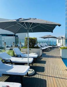 ダーバンにあるPearlviewのプールサイドのラウンジチェアとパラソル