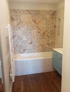 een badkamer met een bad en een tegelwand bij Maison de maître in Bernac-Debat