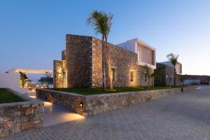 a building with a stone wall and a palm tree at Lindian Poem Villas in Lindos