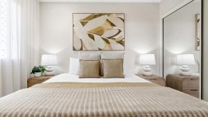 una camera da letto bianca con un letto grande e due lampade di Sundown on Grafton St a Cairns