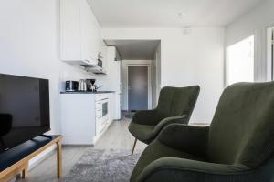 a living room with two green chairs and a television at Convenient Apartment for 3 in Masala +8 photos