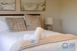 a white bed with a towel on it at Mandurah Luxury on Sutton in Mandurah