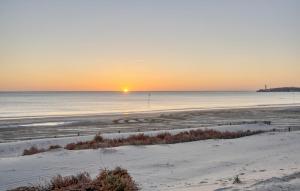 einen Sonnenuntergang über einem Strand mit dem Meer in der Unterkunft Charmant Appartement in Saint-Georges-de-Didonne