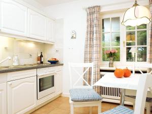 Una cocina con gabinetes blancos y una mesa con naranjas encima. en Enenhoog-Flugente, en Kampen