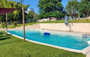 ein Pool mit Sonnenschirm und eine blaue Frisbee im Rasen in der Unterkunft 2 Bedroom Cozy Home In Eyraud-Crempse-Maurens in La Ressegue