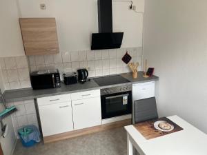 a kitchen with white cabinets and a stove top oven at Ferienwohnung P5 in Schmölln