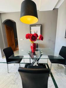a dining room with a glass table with a vase of red flowers at Signature Stay Apartments 6 in Almuñécar