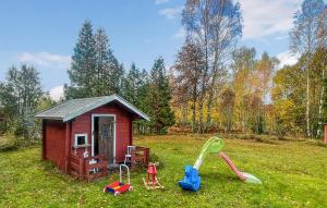 a small red shed with play equipment in the grass at 2 Bedroom Awesome Home In Åmål in Torpane +19 photos