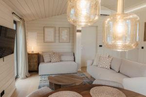 a living room with white furniture and two chandeliers at Resort Wilsumer Berge in Wilsum