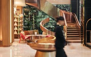 une personne marchant dans un hall avec un escalier en colimaçon dans l'établissement Kin Hotel Thi Sach, à Hô-Chi-Minh-Ville