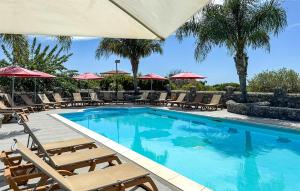 ein großer Swimmingpool mit Liegen und Sonnenschirmen in der Unterkunft Cozy Apartment In Ricadi With Wifi in San Nicolò + 9 Fotos