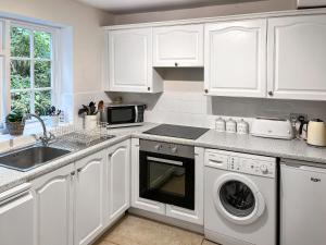 a white kitchen with a sink and a dishwasher at Jennys Cottage in Osmotherley