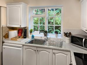 a white kitchen with a sink and a window at Jennys Cottage in Osmotherley
