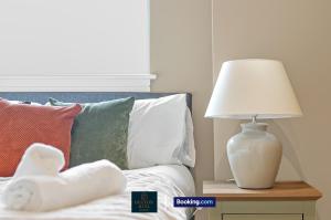 a white lamp sitting on a table next to a bed at Luxury 3BDR Flat - Short Lets & Serviced Accommodation Wembley With Wi-Fi, Gym & Cinema in London +22 photos