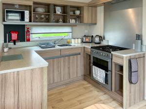 een keuken met houten kasten en een kookplaat met oven bij Arran View Craig Tara in Ayr