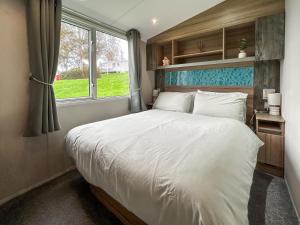 een slaapkamer met een groot wit bed met een raam bij Arran View Craig Tara in Ayr