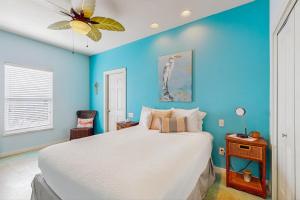 Mustang BeachにあるThe Crystal Troutの青い壁のベッドルーム1室(大きな白いベッド1台付)