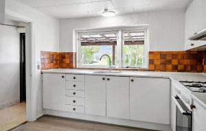 a kitchen with white cabinets and a window at 1 Bedroom Nice Home In Hurup Thy in Ullerup