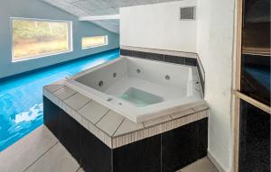 a large bath tub in a bathroom with a swimming pool at Nice Home In Blåvand With Sauna in Blåvand +18 photos