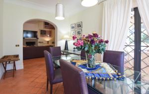 a dining room with a glass table with a vase of flowers at Cozy Home In Tarquinia in Porto Clementino