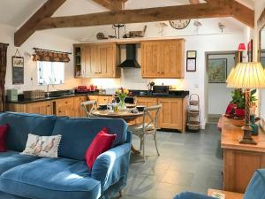 a living room with a blue couch and a kitchen at The Barn, Llanerch Y Felin in Rowen