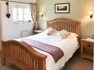 a bedroom with a large wooden bed with white sheets at The Barn, Llanerch Y Felin in Rowen